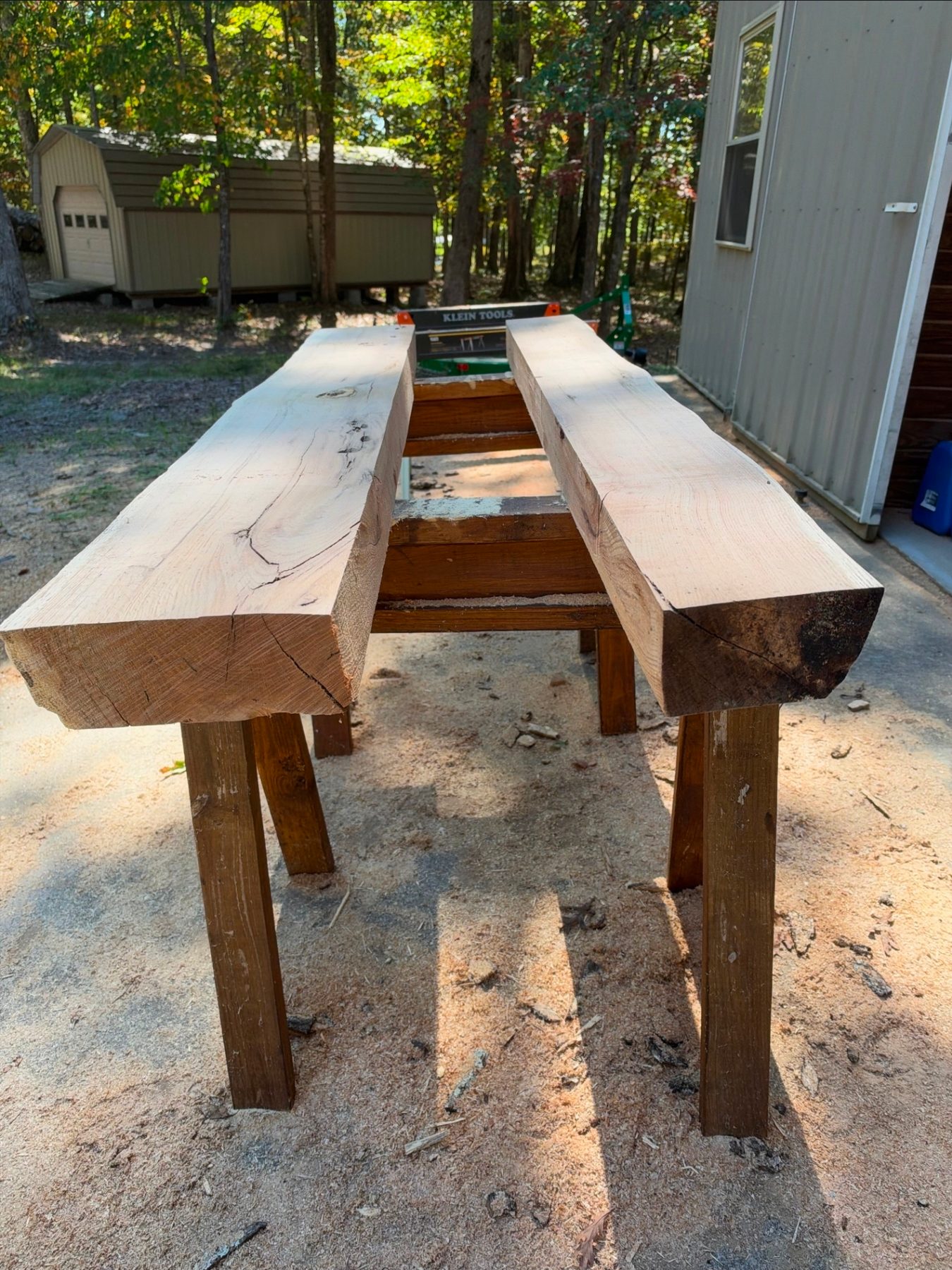 Two sanded red oak mantel beams on sawhorses, bark on the ends — Live Edge Oak Co